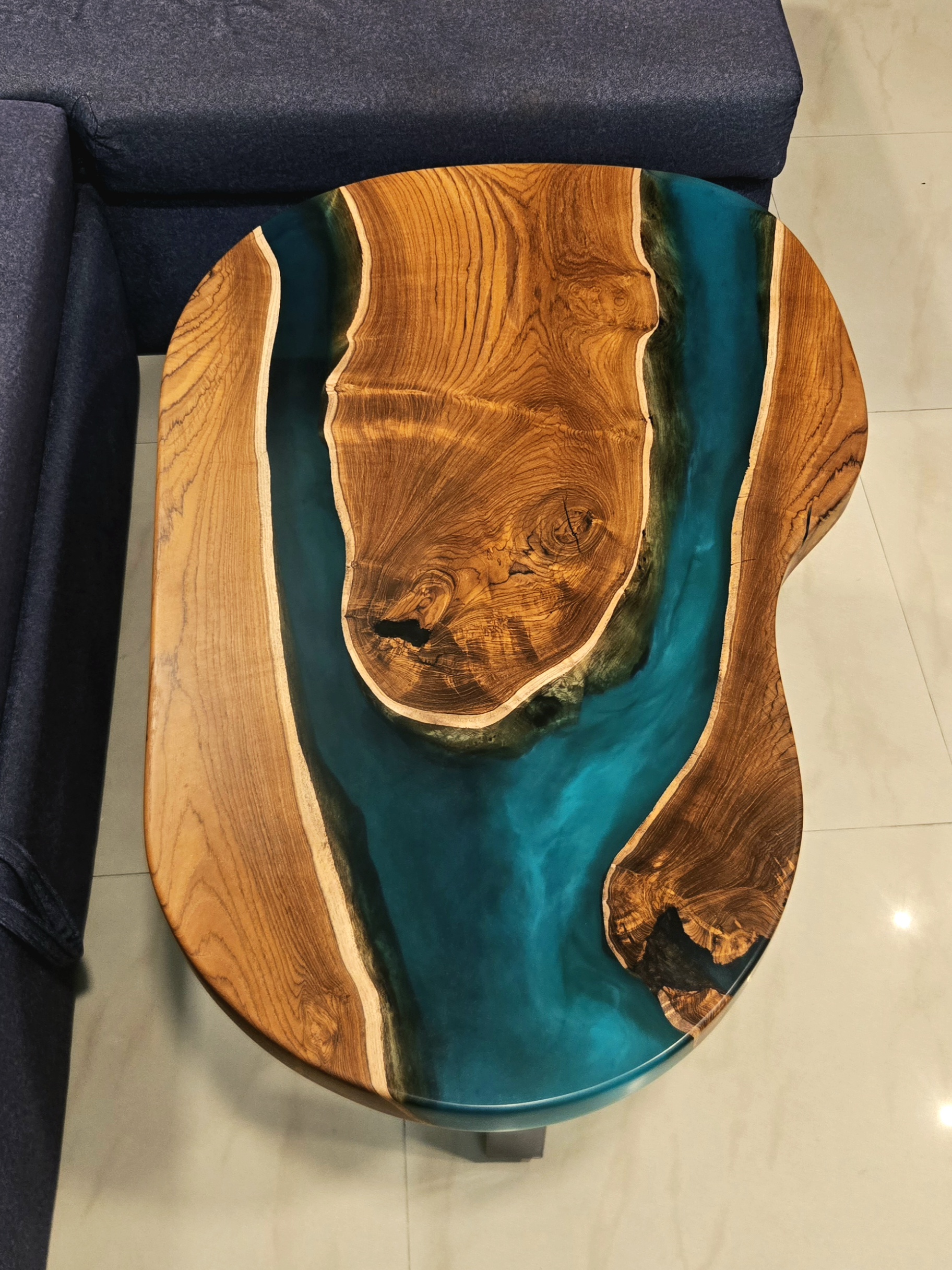Asymmetrical organic teak table with a wide turquoise resin river